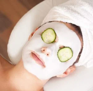 woman relaxing with a facial skin masque and cucumber slices over her eyes
